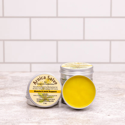Two containers of Arnica Salve on a white surface with a tiled wall background